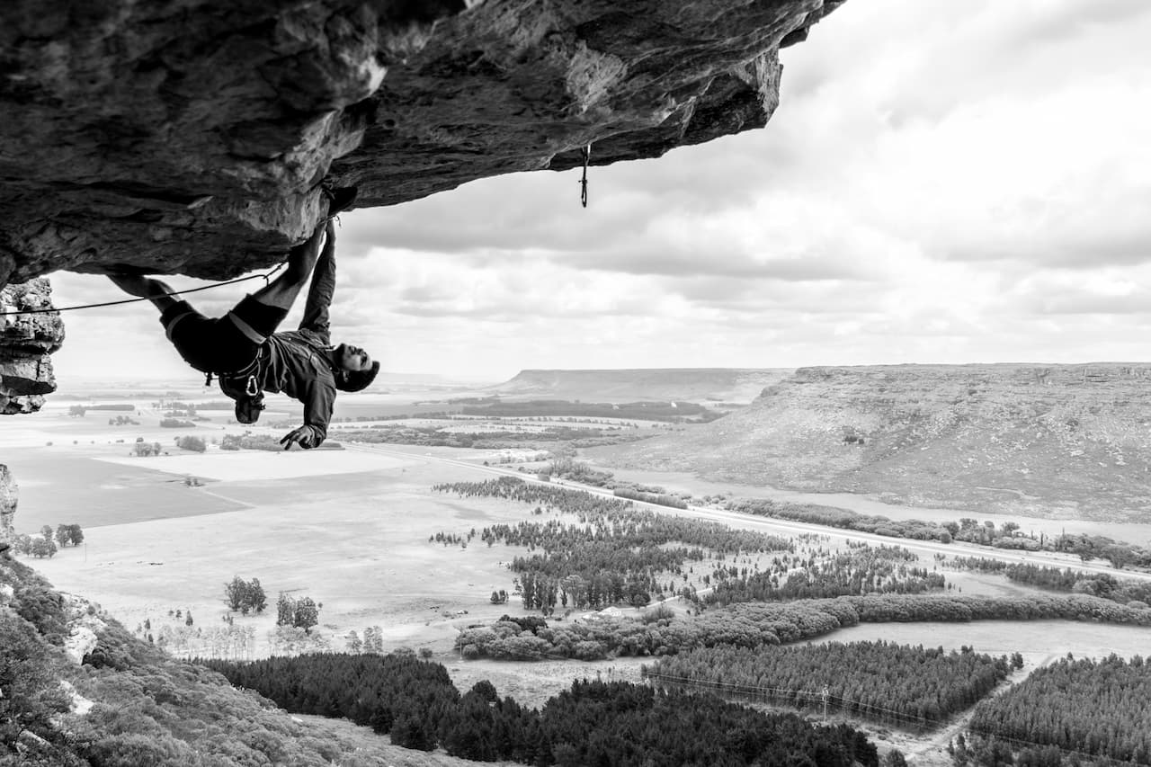 Man climbing in a rock. This section is a roof so he's exposed to a heavy fall if the safety is loose